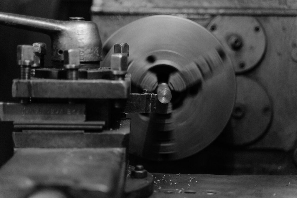 Black and white close-up of an industrial lathe machine showing its intricate mechanical details.