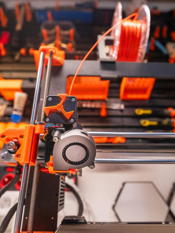 Detailed view of a 3D printer with filament and tools in a workshop setting.